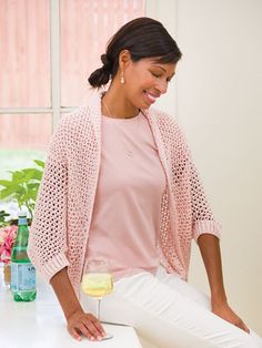 a woman sitting at a table with a glass of wine in her hand and smiling