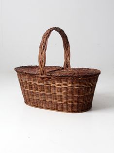 a brown wicker basket with handles on a white background