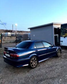 a blue car is parked next to a bus