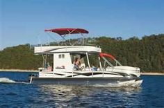 a white boat with people on it traveling in the water near some trees and land