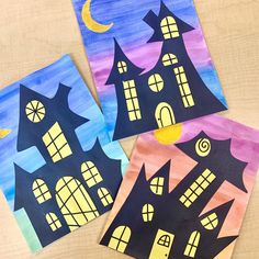 three paper houses painted with different colors and shapes, one on top of the other