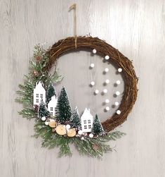 a wreath with white houses and pine cones