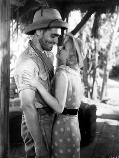 black and white photograph of a man and woman in cowboy hats kissing on the cheek