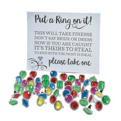 a bunch of colorful brooches sitting on top of a white card with a sign that says put a ring on it