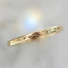 a yellow gold wedding band with leaves on it