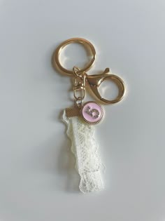 a gold key chain with a pink button on it