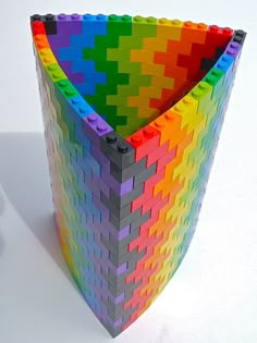 a multicolored basket made out of legos on a white surface with shadows