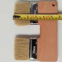 two paint brushes and a measuring tape on top of each other with the same size