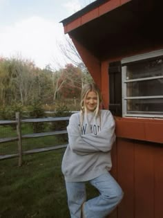 a woman leaning against the side of a red building