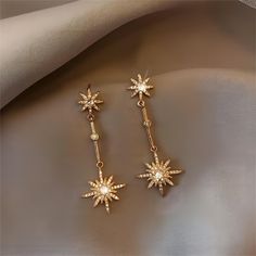 Description: CZ Inlaid Polar Star Boho Dangle Earrings Specifications:Material: Eco-plated Copper, Cubic Zirconia, Artificial Pearl, 18k Gold Species: EarringsSize: 4.4 cm * 1.8 cmWeight: 5 g/pair "Add a touch of celestial charm to your wardrobe with our CZ Inlaid Polar Star Boho Dangle Earrings! These earrings feature a sparkling CZ inlaid polar star design that will make you shine bright like a star. Perfect for adding a fun and playful twist to any outfit!" Elegant Dangle Earrings With Star Charm, Elegant Gold Plated Star Earrings, Celestial Star-shaped Crystal Earrings Gift, Elegant Gold Star-shaped Crystal Earrings, Gold Star-shaped Crystal Earrings For Pierced Ears, Star Making, Polar Star, Star Dangle Earrings, Dangle Earrings Boho