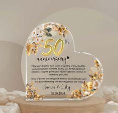 a 50th anniversary card with flowers and leaves in the shape of a heart on a wooden stand