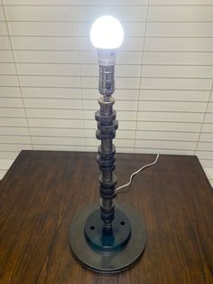 a lamp that is sitting on top of a wooden table in front of a white wall