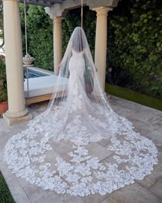 a woman in a wedding dress with a veil on her head is standing near a pool