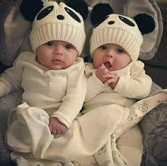 two babies wearing panda hats sitting next to each other