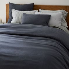 an unmade bed with blue sheets and pillows