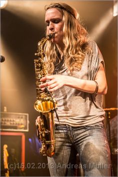 a man with long hair playing a saxophone