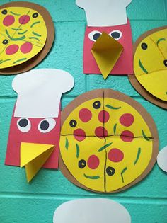 paper plates with cut out pizzas on them are hanging from the wall in front of a blue painted brick wall