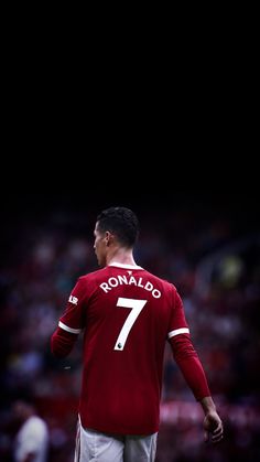 a man standing on top of a soccer field wearing a red shirt and white shorts