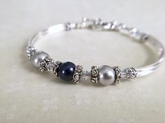 This subtle and delicate looking bangle bracelet is made with one midnight blue and two silver Swarovski Crystal pearls joined with sterling silver star bead caps that separate the 4mm Swarovski Crystal AB bicones. Sterling silver plated curved tube beads and a sweet heart toggle completes this comfortable bangle bracelet. Pictures are nice but by no means do justice to the actual piece! This is truly a rich and classy looking bracelet. * Matching earrings https://www.etsy.com/listing/461992687/ Silver Bracelet Jewelry For Mother Of The Bride, Silver Bracelet For Mother Of The Bride Jewelry, Silver Bracelet For Mother Of The Bride, Silver Pearl Bangle For Anniversary, Silver Pearl Bracelet For Bridesmaid Gift, Adjustable Silver Beaded Bracelets For Bridesmaid Gift, Silver Pearl Bracelet For Bridesmaid, Personalized Elegant Silver Beaded Bracelets, Silver Bracelet Jewelry For Bridesmaid Gift