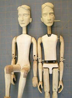 two wooden mannequins sitting next to each other