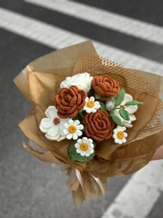 a person holding a bouquet of flowers in their hand on the side of the road