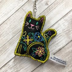 a black cat keychain hanging on a white wooden surface with a tag attached to it