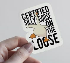 a hand holding up a sticker that says certified silly goose on the loose side