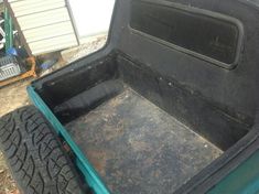 the back end of a blue truck with mud on it's bed and wheels