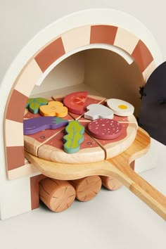 a toy pizza oven with wooden spoons in it