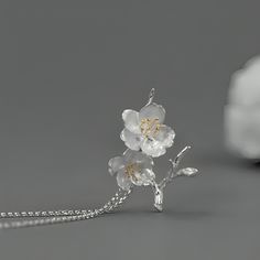 Introducing our exquisite pendant featuring a delicate design of cherry blossoms crafted in sterling silver. The intricate details of the flowers are beautifully highlighted with gold plating on the stamens, adding a touch of elegance and sophistication. The pendant captures the essence of spring, symbolizing renewal and beauty. It hangs gracefully from a matching sterling silver chain, making it a timeless accessory suitable for any occasion. Delicate Spring Jewelry For Anniversary, Delicate Jewelry For Spring Anniversary, Delicate Jewelry For Anniversary In Spring, Elegant Sterling Silver Spring Jewelry, Elegant Sterling Silver Jewelry For Spring, Spring Sterling Silver Jewelry With Flower Charm, Spring Sterling Silver White Jewelry, Spring White Sterling Silver Jewelry, Elegant Blossom-colored Spring Jewelry