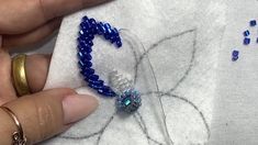 someone is making beaded jewelry on a white shirt with blue beads and gold rings