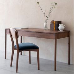 a wooden desk with a chair and vase on it