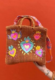 Get ready to elevate your style with this gorgeous Mexican Embroidered Bag, handmade with love and care in Mexico! Crafted from natural fiber, this bag features stunning Corazon Mexicano embroidery that pays homage to traditional Mexican artistry. The hand-knitted strap from Chiapas, Mexico adds a unique and authentic touch to this one-of-a-kind piece. This Boho Chic Bag is not only beautiful but also versatile. Wear it for your everyday outings, a night out in town, or even bring it along to th Handmade Multicolor Embroidered Shoulder Bag For Vacation, Handmade Multicolor Embroidered Bags For Vacation, Handmade Multicolor Embroidery Bags For Vacation, Handmade Multicolor Embroidered Shoulder Bag For Beach, Natural Embroidered Straw Bag For Daily Use, Embroidered Crochet Tote Bag For Vacation, Embroidered Brown Vacation Bag, Bohemian Jute Bag As Gift, Brown Embroidered Vacation Bag