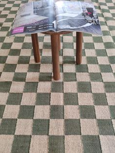 an open magazine sitting on top of a wooden table with checkered pattern covering it