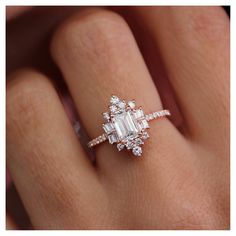 a woman's hand with an engagement ring on it and the center stone is surrounded by diamonds