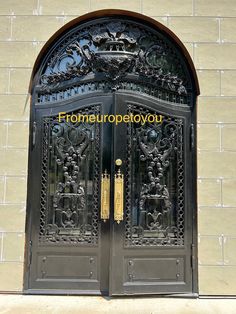 an ornate iron door with gold handles on a brick wall