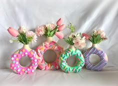 three vases filled with flowers and decorated doughnuts