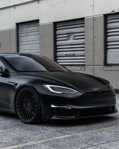 a black tesla parked in front of a building