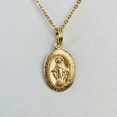 "A beautiful and delicate 14K solid yellow gold engraved Miraculous Medal pendant charm featuring the Virgin Mary on one side and the Marian cross on the other, which makes the perfect communion or confirmation gift. There is a prayer around Mary on the front of the pendant which says: O Mary conceived without sin pray for us who have recourse to thee. The pendant measures 9mm wide by 14mm including bail but without the split ring It can be used as a necklace pendant or a bracelet charm. The pen Yellow Gold Necklace With 14k Stamped Oval Pendant, Yellow Gold Oval Pendant Necklace Stamped 14k, 14k Gold Necklace With Miraculous Medal For Anniversary, Yellow Gold Medallion Charm Necklaces, Yellow Gold 14k Stamped Oval Pendant Necklace, Engraved 14k Yellow Gold Filled Charm Necklace, Yellow Gold Medallion Charm Necklace 14k, Dainty Oval Yellow Gold Charm Necklaces, Dainty Yellow Gold Oval Pendant Charm Necklace