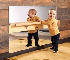 two toddlers standing in front of a mirror