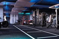 there are many machines in the gym with blue lights on them and black flooring