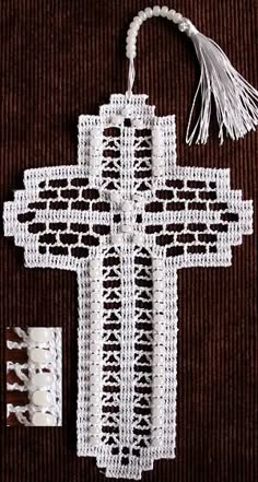 a crocheted cross with tassels hanging from it's sides on a brown background