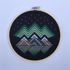 a cross stitched landscape with mountains and stars