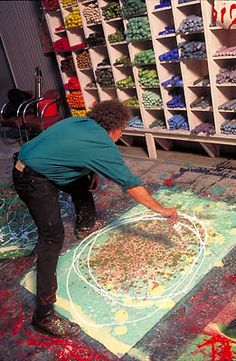 a man is drawing on the ground with colored chalks