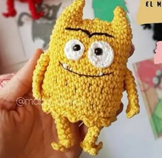 a crocheted yellow object with eyes and hands holding it up to the camera