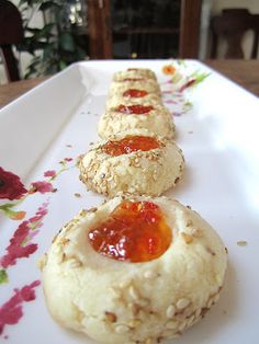 three biscuits with jam on them sitting on a white plate