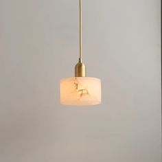 a white and gold colored light hanging from a ceiling fixture in a room with gray walls