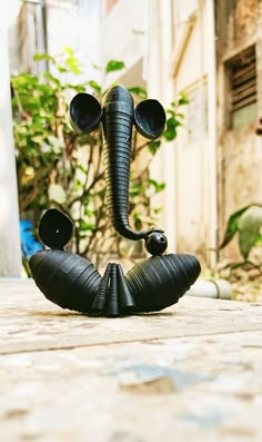 an elephant statue sitting on top of a wooden table next to a tree and building