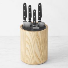 four knives in a wooden holder with black handles