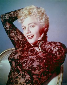 an old photo of a woman with blonde hair wearing a black lace dress and smiling